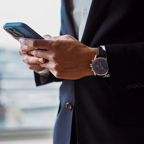 Geschäftsmann im Anzug nutzt Smartphone - Stundenbuchung Limousinenservice München